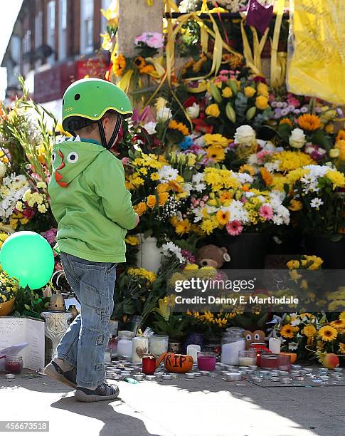 Young boy looks at flowers left at the Hanwell clock tower in memory of Alice Gross on October 5, 2014 in London, England. A body believed to be that...