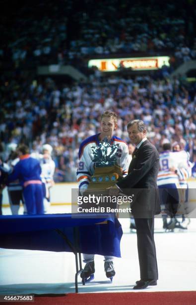 Wayne Gretzky of the Edmonton Oilers is presented the Conn Smythe Trophy from John Ziegler after the Edmonton Oilers defeated the Boston Bruins in...