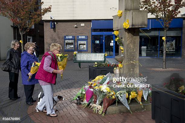 Women prepare to place a floral tribute at the base of the Eccles Cross for murdered aid worker Alan Henning in Eccles, north west England on October...