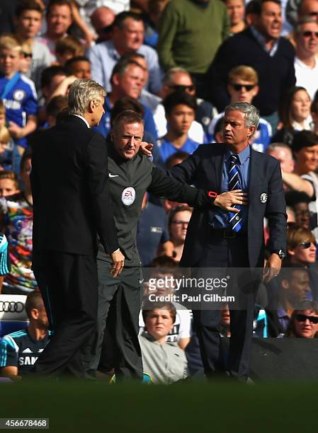 Fourth Official Jonathan Moss comes between Managers Arsene Wenger of Arsenal and Jose Mourinho manager of Chelsea during the Barclays Premier League...
