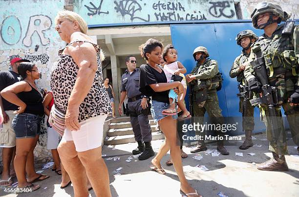 Brazilian soldiers keep watch as people wait to enter a polling station in the Complexo da Mare favela, or community, on the day of national...