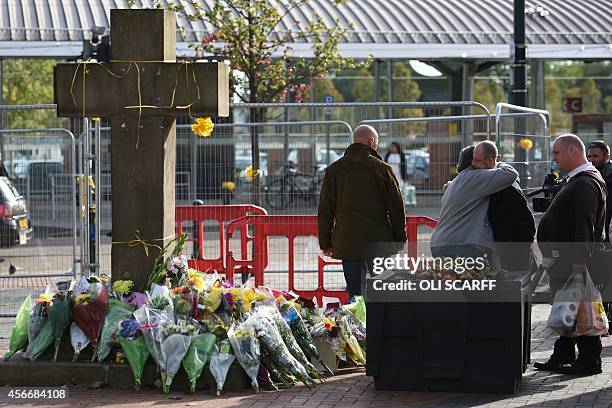 Members of the public observe the floral tributes at the base of the Eccles Cross for murdered aid worker Alan Henning in Eccles, north west England...