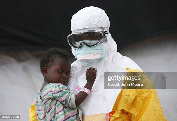 Doctors Without Borders , health worker in protective clothing holds a child suspected of having Ebola in the MSF treatment center on October 5, 2014...