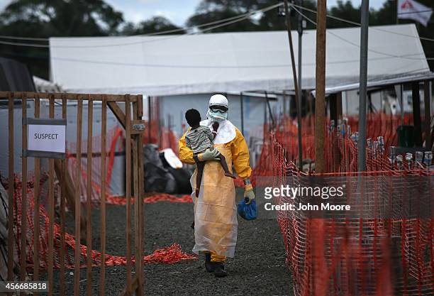 Doctors Without Borders , health worker in protective clothing carries a child suspected of having Ebola in the MSF treatment center on October 5,...