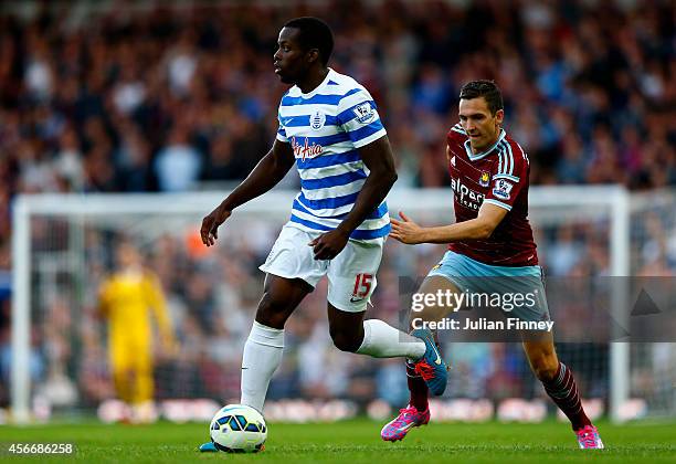 Nedum Onuoha of QPR runs with the ball in front of Stewart Downing of West Ham during the Barclays Premier League match between West Ham United and...