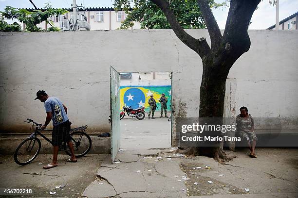 Brazilian soldiers keep watch outside as people gather inside a polling station in the Complexo da Mare favela, or community, on the day of national...
