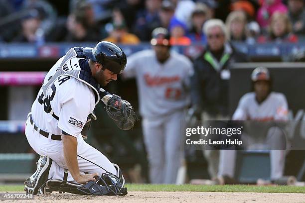 Alex Avila of the Detroit Tigers reacts after being hit with a foul tip in the sixth inning against the Baltimore Orioles during Game Three of the...