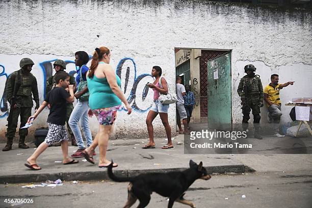 Brazilian soldiers keep watch outside the entrance to a polling station in the Complexo da Mare favela, or community, on the day of national...