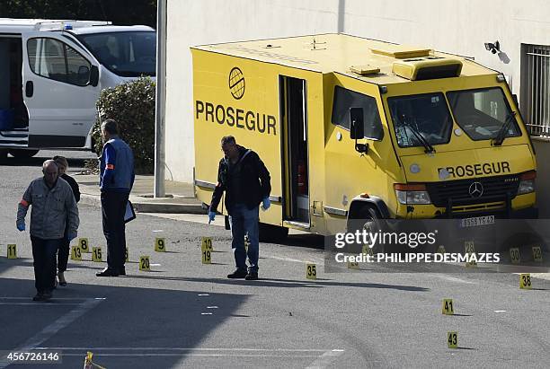 French forensic experts search for evidence near an armoured truck of the Prosegur company after it was attacked by a commando on October 6, 2014 at...