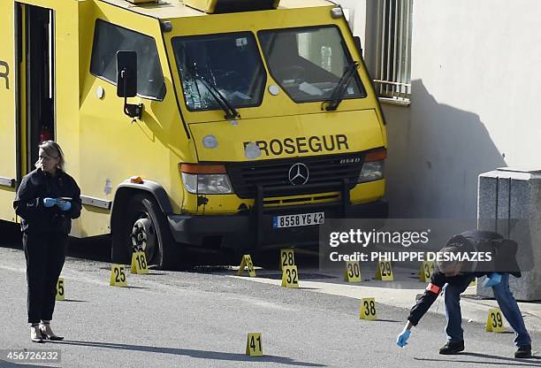 French forensic experts search for evidence near an armoured truck of the Prosegur company after it was attacked by a commando on October 6, 2014 at...