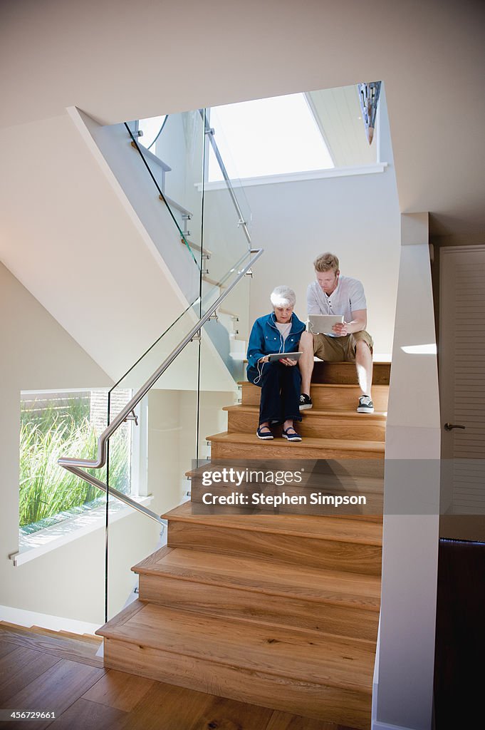 Woman and her grandson on tablets on stairs