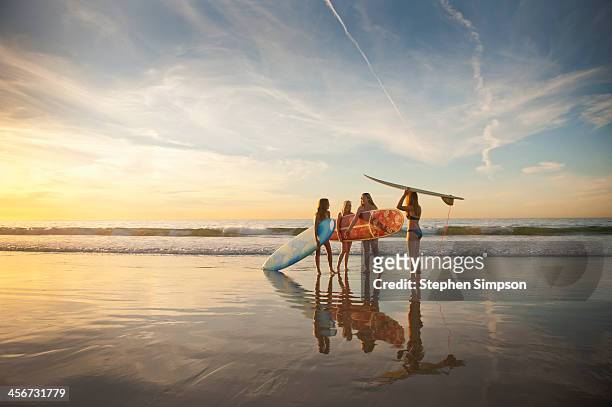 teen girls going surfing, low tide, late afternoon - californie surf stockfoto's en -beelden