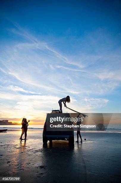 sunset, girls at beach loading the car - us girls on the beach stock-fotos und bilder