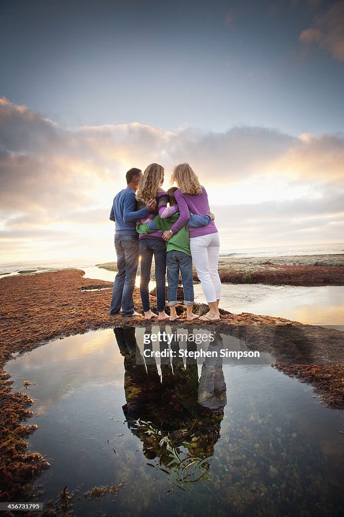 Family exploring tide pools at sunset