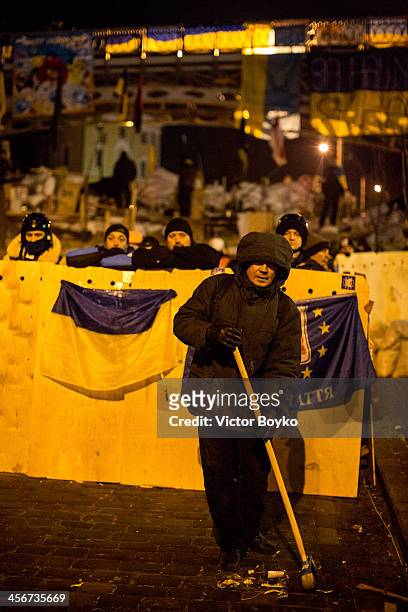 Protester cleans the street near a makeshift barricade near Instytutska street on Maidan Square on December 14, 2013 in Kiev, Ukraine....