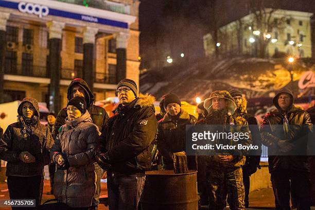Protesters watch the TV screen on Maidan Square as protests continue on December 14, 2013 in Kiev, Ukraine. Anti-government protests began three...