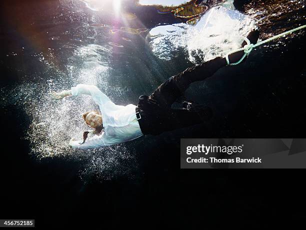 businessman being pulled by rope underwater - business enterprise survival endurance stock pictures, royalty-free photos & images