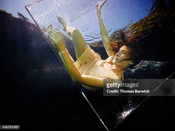 underwater view of woman falling in glass box - glass box stockfoto's en -beelden