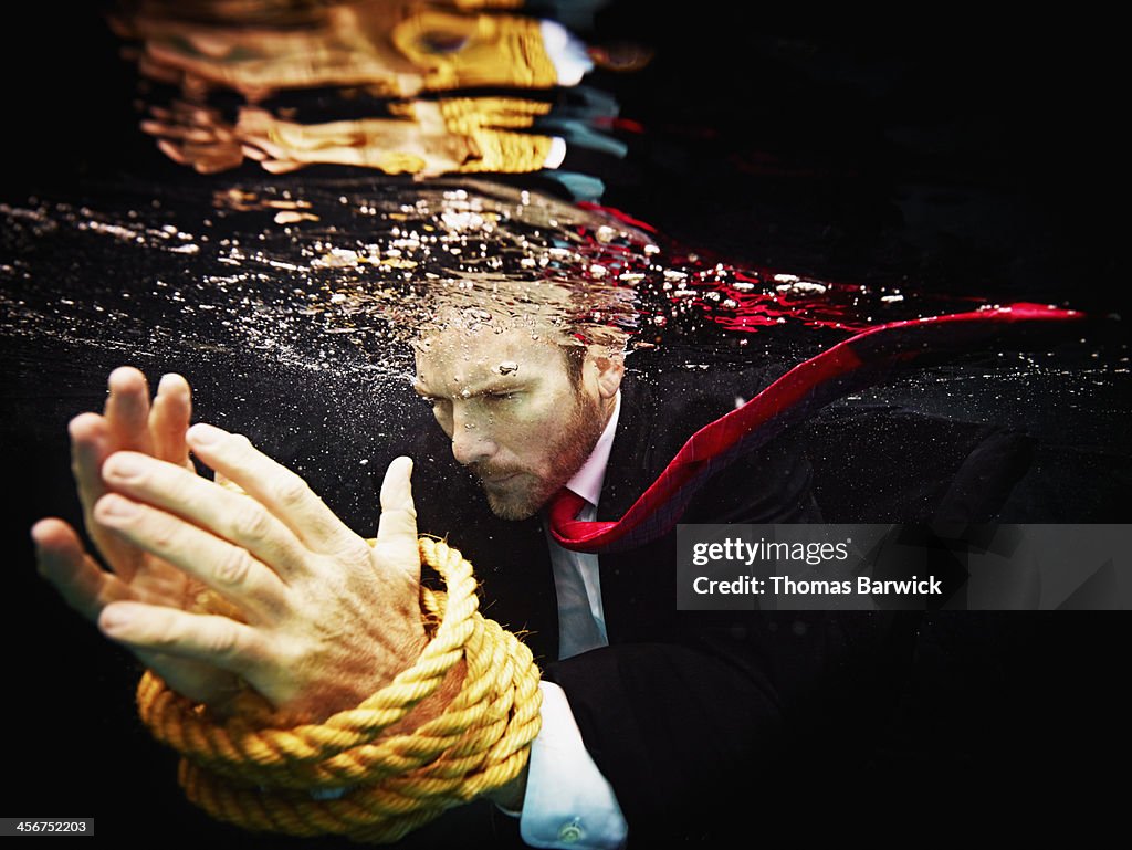 Businessman underwater with hands tied