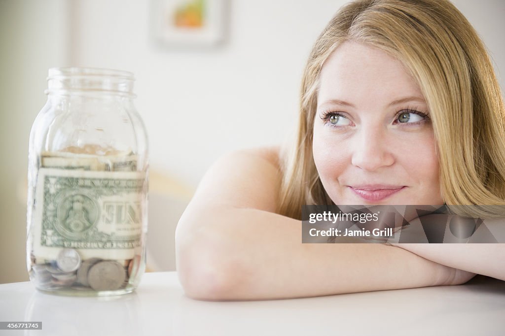 Woman with jar of money, looking away in thought