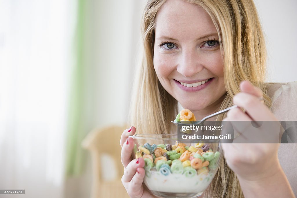 Woman eating colorful cereal, smiling