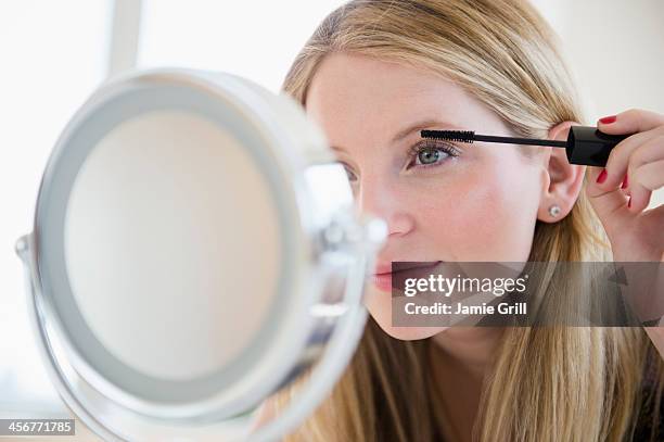 woman putting on mascara in mirror - applying mascara stock pictures, royalty-free photos & images