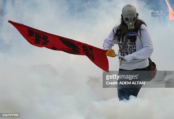Person holds a flag as police uses tear gas and water cannon on October 7, 2014 in Ankara against demonstrators who protest against attacks launched...