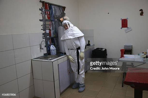 Navy microbiologist Lt. Jimmy Regeimbal, dressed in an anti-contamination suit, cools off beside an air-conditioning vent after testing blood samples...