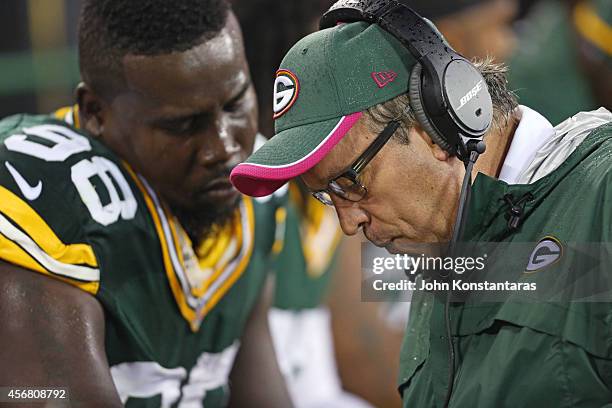 Letroy Guion of the Green Bay Packers with defensive line coach Mike Trgovac during the second quarter of the NFL game on October 02, 2014 at Lambeau...