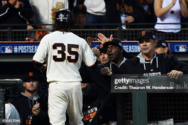 Brandon Crawford of the San Francisco Giants is welcomed back to the dugout after he scored on a walk by Gregor Blanco in the second inning against...