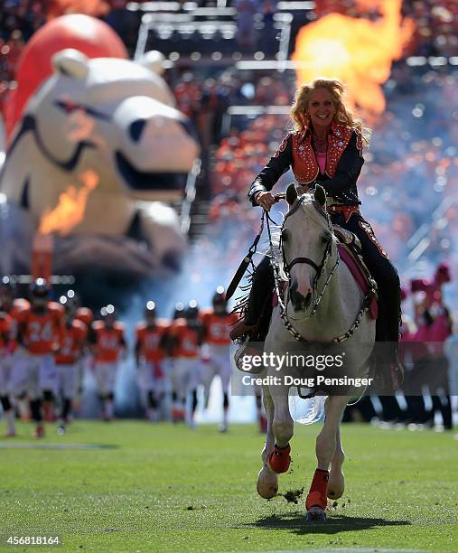 Ann Judge-Wegener rides Thunder the mascot as they escort the Denver Broncos onto the field to face the Arizona Cardinals at Sports Authority Field...