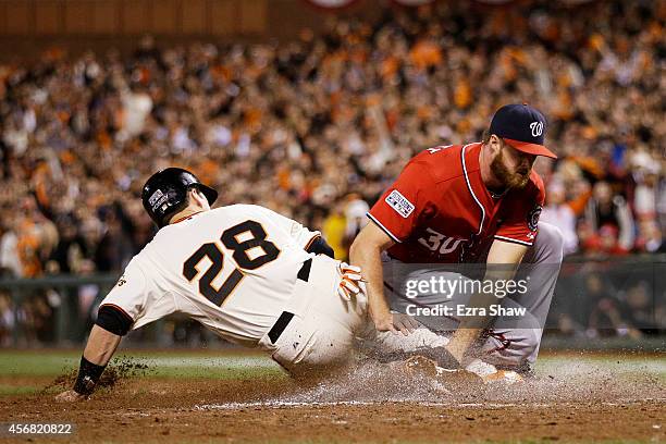 Buster Posey of the San Francisco Giants is out at home plate by Aaron Barrett of the Washington Nationals in the seventh inning during Game Four of...