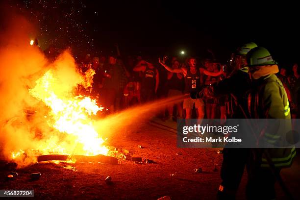 Crowd watch on as firemen extinguish a large fire burning in the "Ute Paddock" camp ground on the second day of the 2014 Deni Ute Muster at the Play...