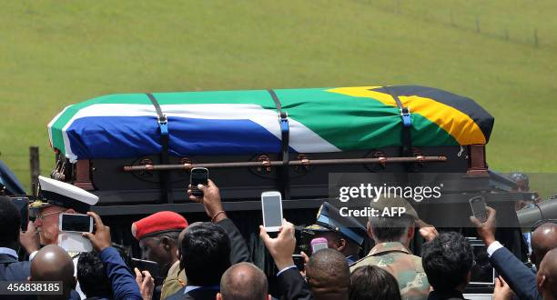 People take pictures as the coffin of South African former president Nelson Mandela is carried on a gun carrier for a traditional burial during his...