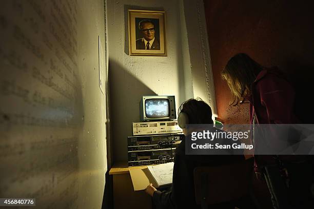 Young visitors look at a reconstructed Stasi secret police surveillance corner under a portrait of former East German communist leader Erich Honecker...