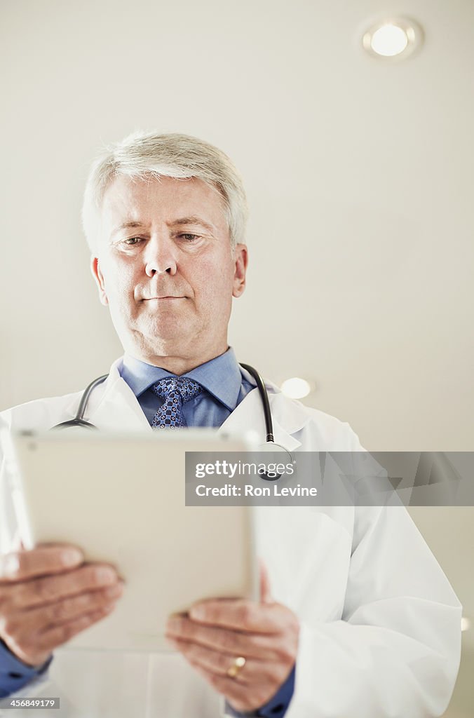 Mature doctor looking at digital tablet in clinic