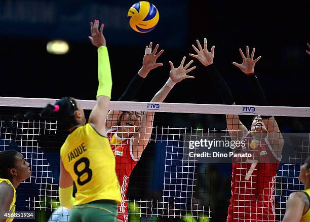 Junjing Yang of China spikes the ball against to Fernanda Rodrigues and Fabiana Claudino of Brazil during the FIVB Women's World Championship pool H...