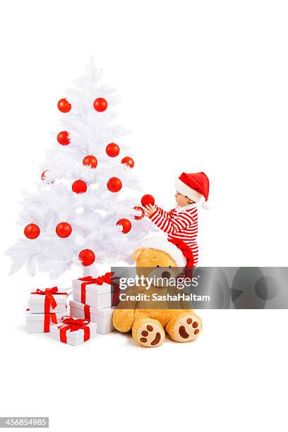 baby santa decorates christmas tree - eenjarig plantenkenmerk stockfoto's en -beelden