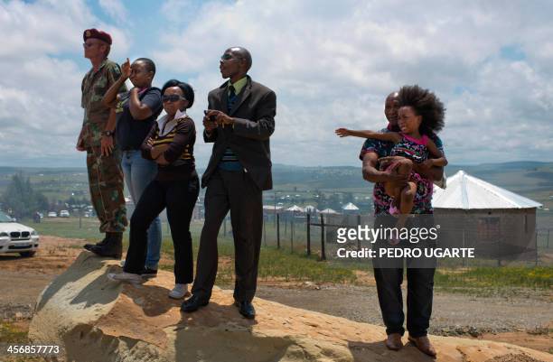 People react as the coffin of late South African former president Nelson Mandela is buried in the compound of his former home in Qunu on December 15,...