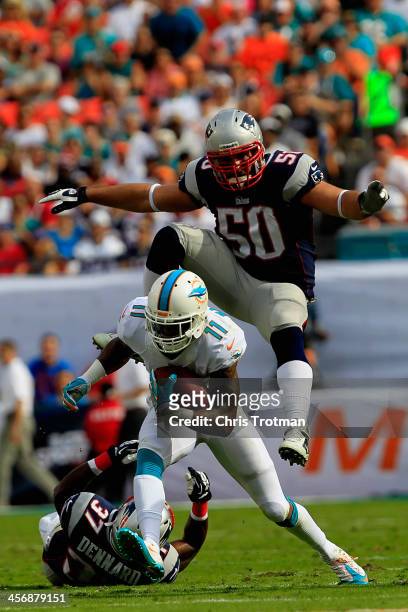 Mike Wallace of the Miami Dolphins rushes with the ball under pressure from Rob Ninkovich of the New England Patriots and Alfonzo Dennard of the New...