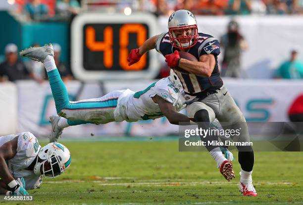 Julian Edelman of the New England Patriots escapes a tackle from Nolan Carroll of the Miami Dolphins during a game at Sun Life Stadium on December...