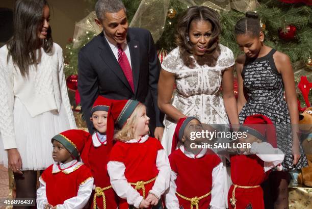 President Barack Obama, First Lady Michelle Obama and their daughters Sasha and Malia pose for photographs alongside children dressed as elves, who...