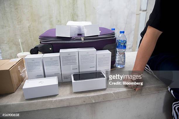 Man sits next to Apple Inc. IPhone 6 and iPhone 6 Plus smartphones for sale outside the company's Central district store in Hong Kong, China, on...