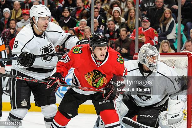 Drew Doughty of the Los Angeles Kings and Andrew Shaw of the Chicago Blackhawks stand in position next to goalie Ben Scrivens of the Los Angeles...