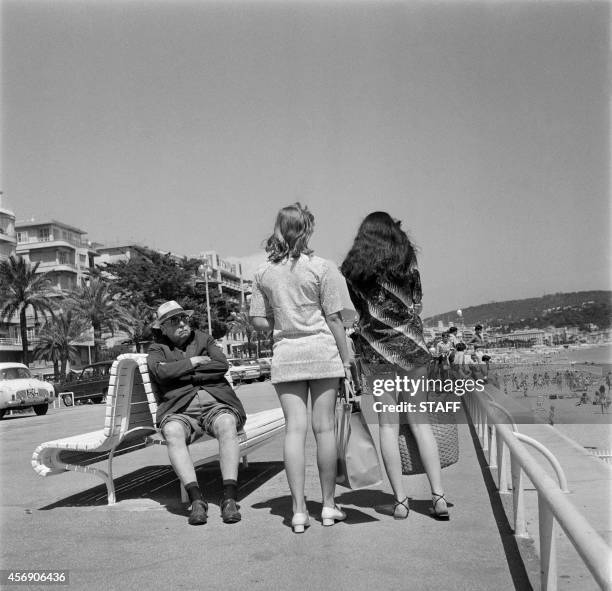 His trousers' legs rolled to take advantage of the sun, an old man looks toward two girls wearing mini-skirt, on July 13, 1969 in Nice.