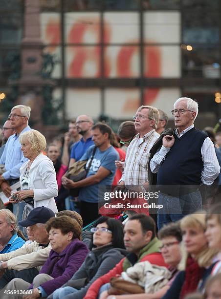 People standing on Augustplatz square watch a live broadcast of a prayer for peace given at the nearby Nikolaikirche church as part of commemorations...