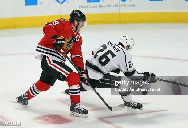 Jonathan Toews of the Chicago Blackhawks shoots the puck between the legs of Slava Voynov of the Los Angeles Kings at the United Center on December...