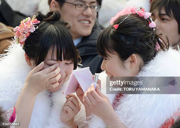 Year-old local woman dressed in kimono helps her friend to check her false eyelashes during the ceremony for their "Coming-of-Age Day" celebration at...