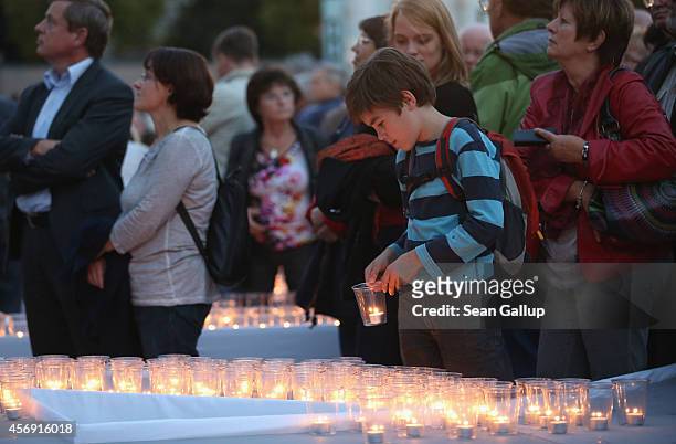 People arrive to light candles on Augustplatz square during commemorations marking the 25th anniversary of the mass protests in Leipzig that preceded...