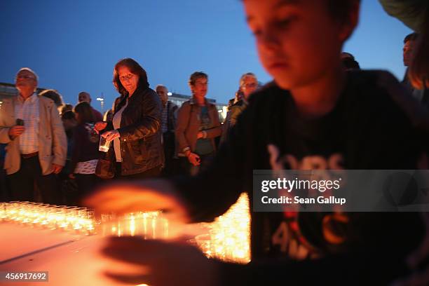 People arrive to light candles on Augustplatz square during commemorations marking the 25th anniversary of the mass protests in Leipzig that preceded...